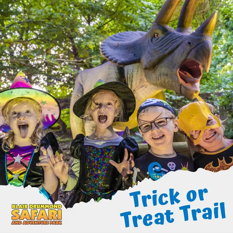 Children in Halloween costumes in front of a dinosaur model, promoting the Blair Drummond 'Trick or Treat Trail'