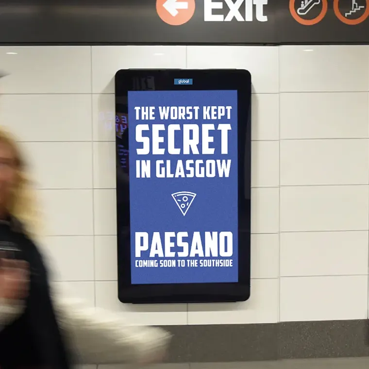 A digital billboard in a subway station displays a blue banner with white text that reads, The Worst Kept Secret In Glasgow - Coming Soon to the Southside.