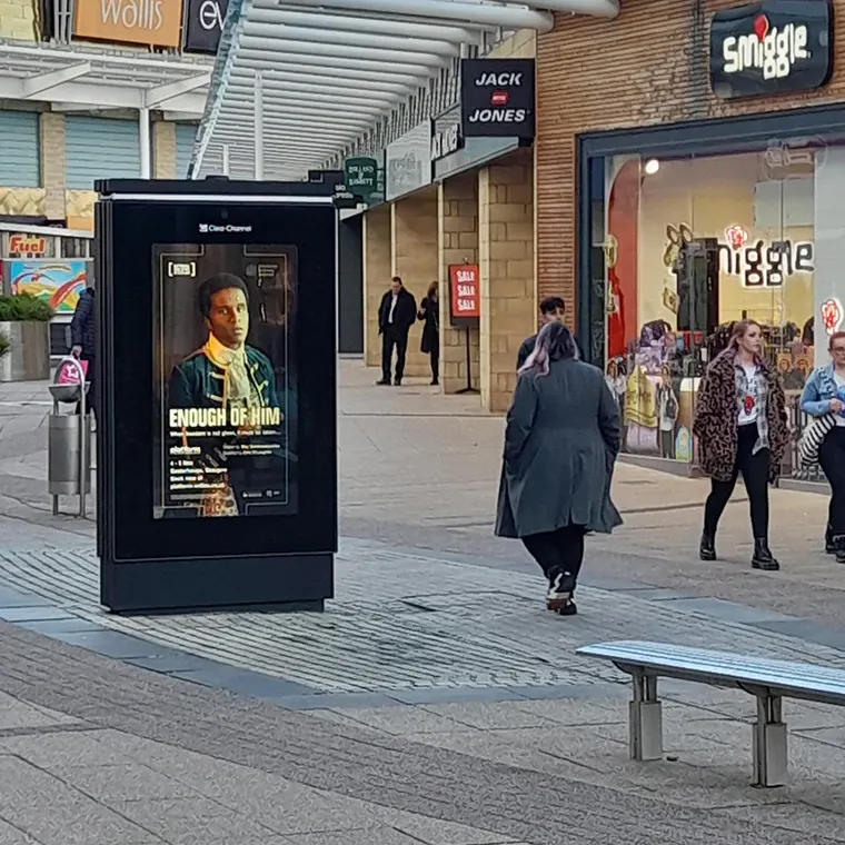 A digital street billboard at the Glasgow Fort shopping center displaying an ad for the National Theatre of Scotland's production of Enough of Him.