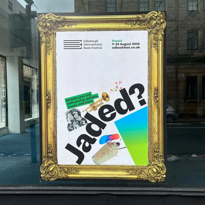 A promotional poster for the Edinburgh International Book Festival displayed behind a window in an ornate gold frame. The poster features the word Jaded? from the 2025 "Repair" campaign.