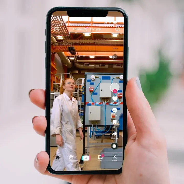 A phone showing a City of Glasgow College TikTok video of an engineering student in a workshop