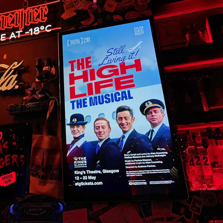 A digital poster for 'The High Life: The Musical' at the King's Theatre, Glasgow, 12 to 23 May, in a bar