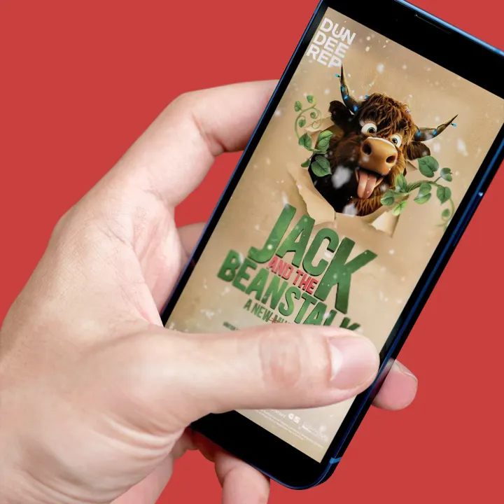 A hand holding a phone showing the Dundee Rep 'Jack and the Beanstalk' advert with a cartoon Highland cow