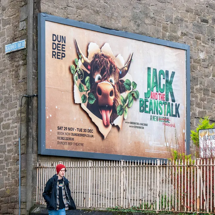 A man walking past a Dundee Rep 'Jack and the Beanstalk' billboard
