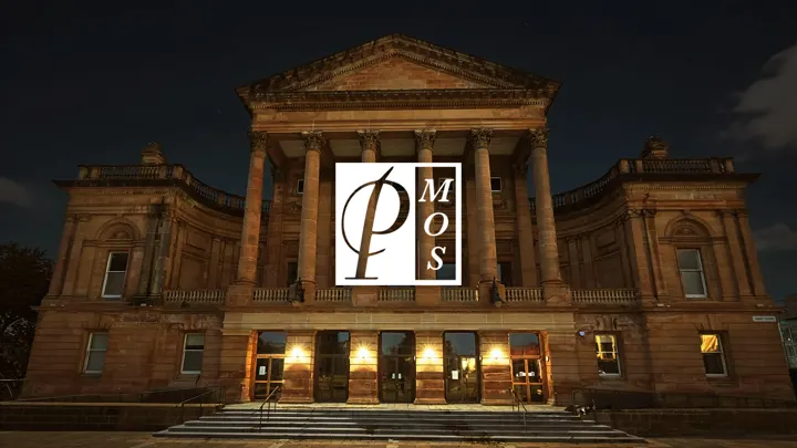 Paisley Town Hall lit up at night with the Paisley Musical and Operatic Society logo