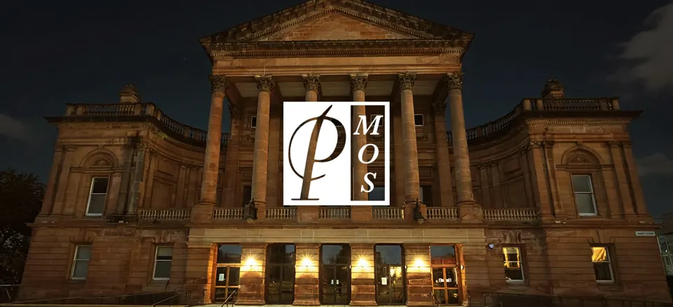 Paisley Town Hall lit up at night with the Paisley Musical and Operatic Society logo
