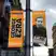 Two orange banners for the TRNSMT festival hang from a street pole in Glasgow. One banner says CHOOSE GEORGE EZRA, the other features a portrait of the artist with the date 7th July.