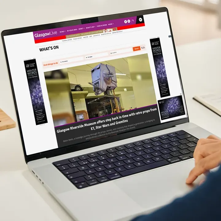 A laptop showing 'Winter Words Festival' banner adverts on the Glasgow Live website