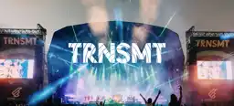 A photograph of one of the night shows at the TRNSMT Festival in Glasgow, showing large TRNSMT branding and people sitting on shoulders to get a better view of the performers