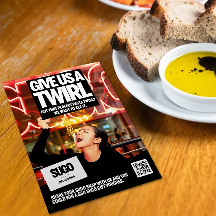 A Sugo 'Give us a Twirl' flyer beside bread and olive oil: share your pasta twirl to win a £50 voucher