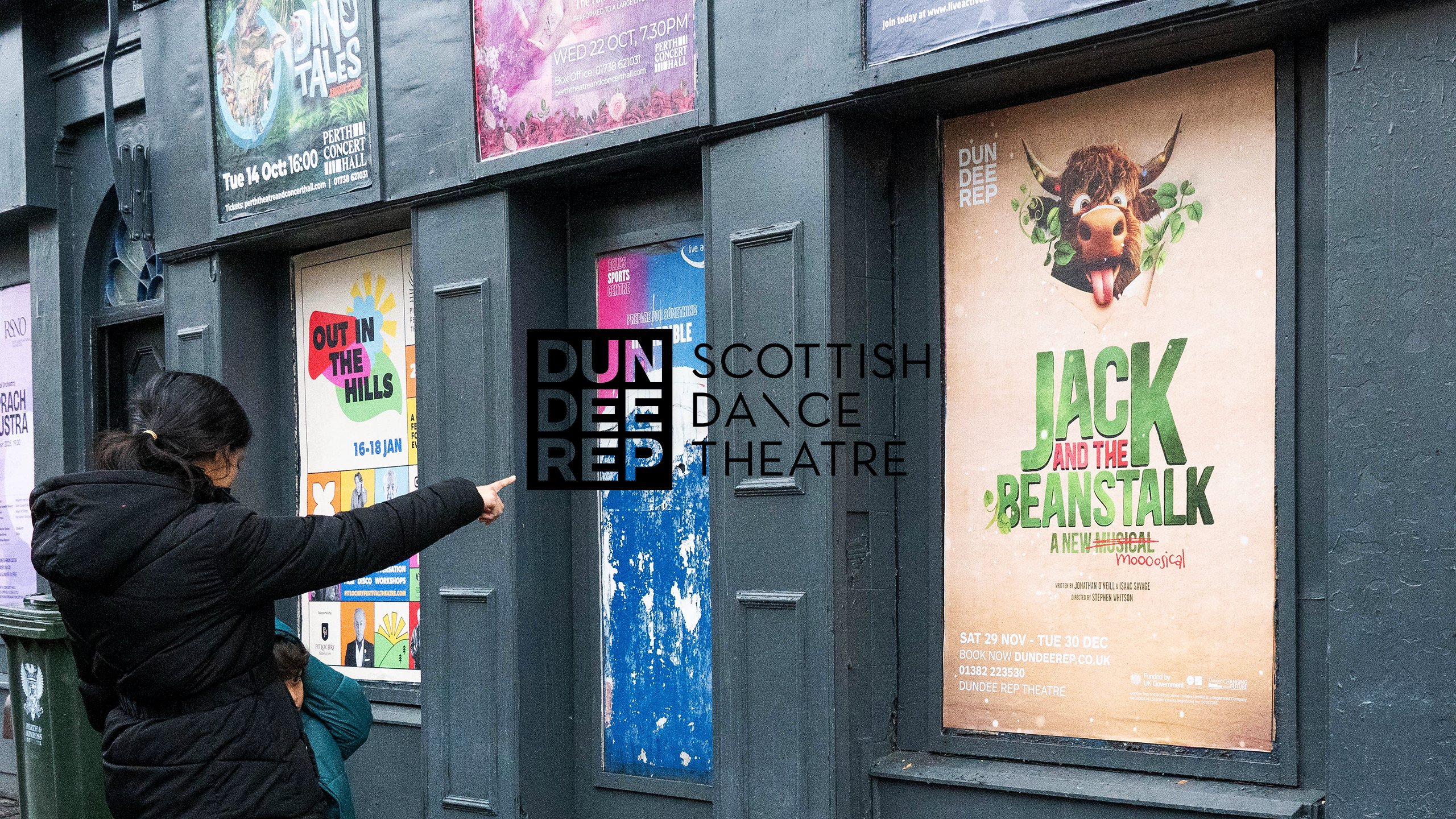 A woman pointing at a Dundee Rep 'Jack and the Beanstalk' poster outside the theatre