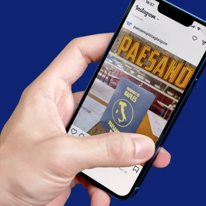 A mobile phone showing Paesano Pizza Glasgow social media post with a passport to Naples image as part of their campaign
