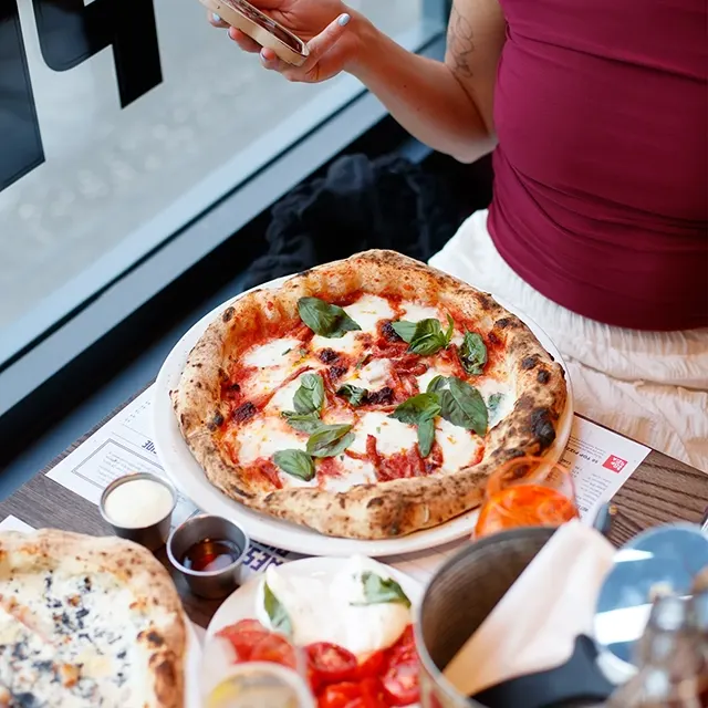 A woman enjoying a pizza at Paesano Pizza
