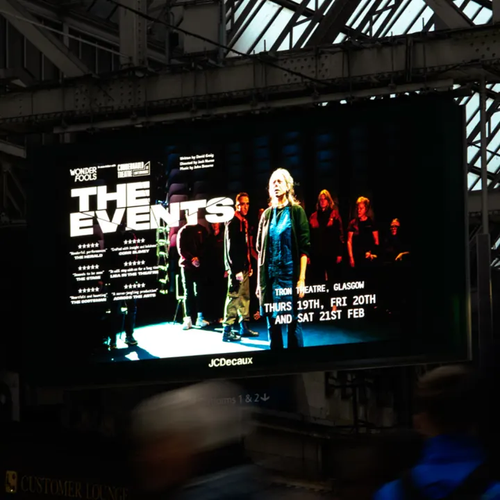 A digital billboard at Glasgow Central Station advertising 'The Events' at the Tron Theatre, 19th to 21st February