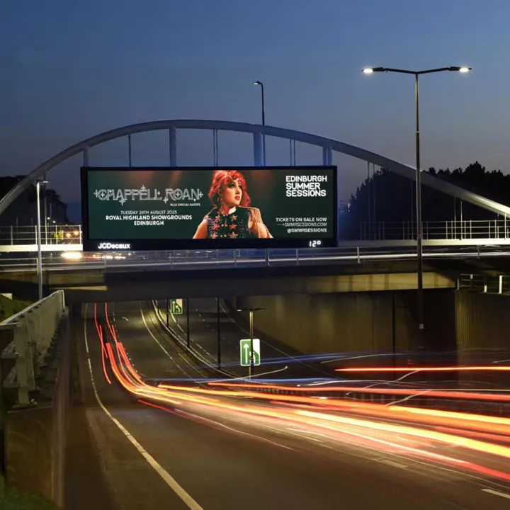 A large digital billboard at dusk over a highway advertising Chappell Roan for Edinburgh Summer Sessions at the Royal Highland Showgrounds on Tuesday, August 26th, 2025.