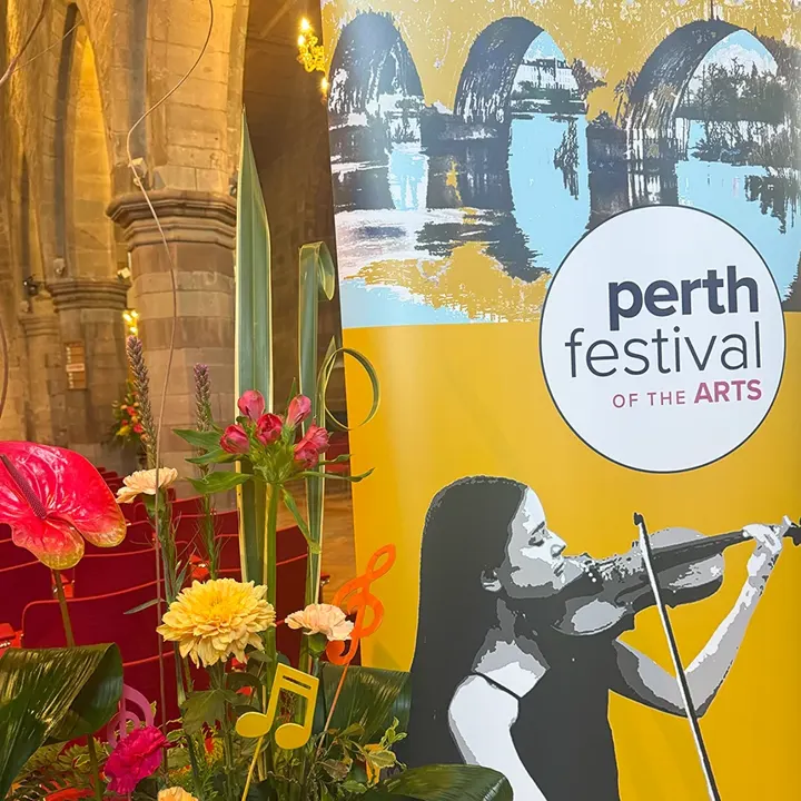 A Perth Festival of the Arts banner of a violinist beside a floral display