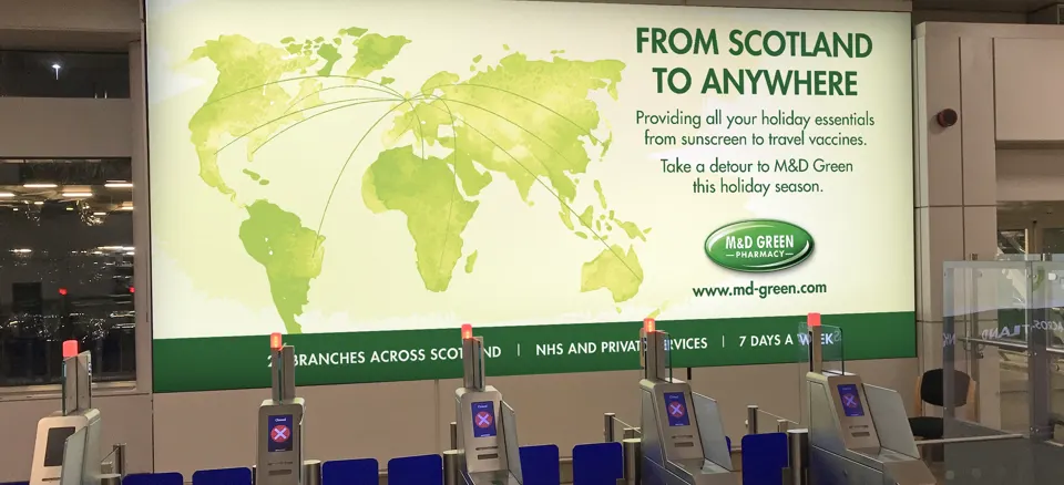 Large-scale OOH advertising, showing an M&D Green Pharmacy banner at airport security stops