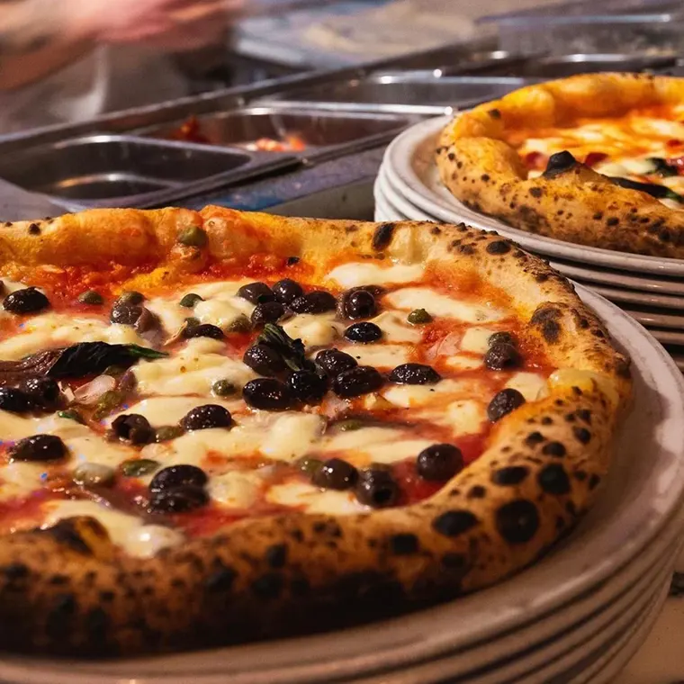 A Paesano pizza topped with mozzarella and black olives, fresh from the oven
